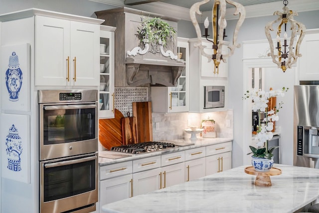 kitchen with pendant lighting, tasteful backsplash, white cabinetry, light stone counters, and stainless steel appliances