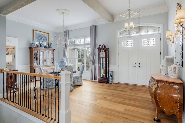 foyer entrance with an inviting chandelier, ornamental molding, light hardwood / wood-style flooring, and beamed ceiling