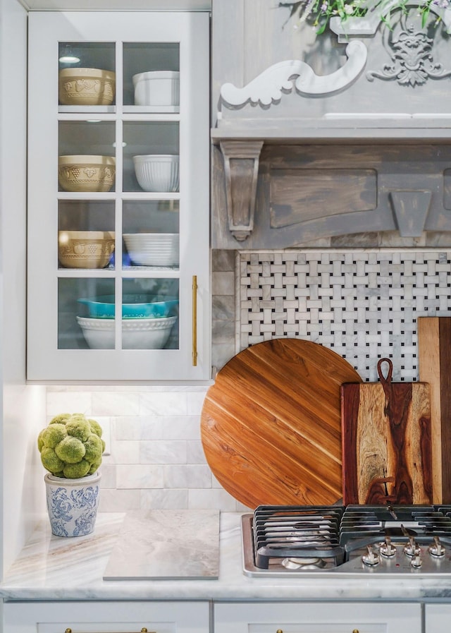 interior details with backsplash, stainless steel gas cooktop, and white cabinets