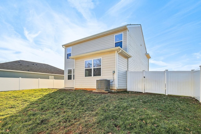 rear view of house featuring central AC unit and a lawn