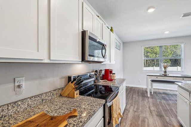 kitchen with light stone counters, appliances with stainless steel finishes, and white cabinets