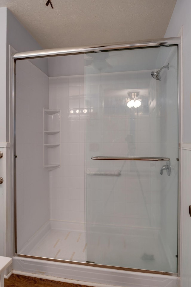 bathroom with a shower with shower door and a textured ceiling