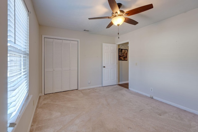 unfurnished bedroom with light carpet, a closet, and ceiling fan