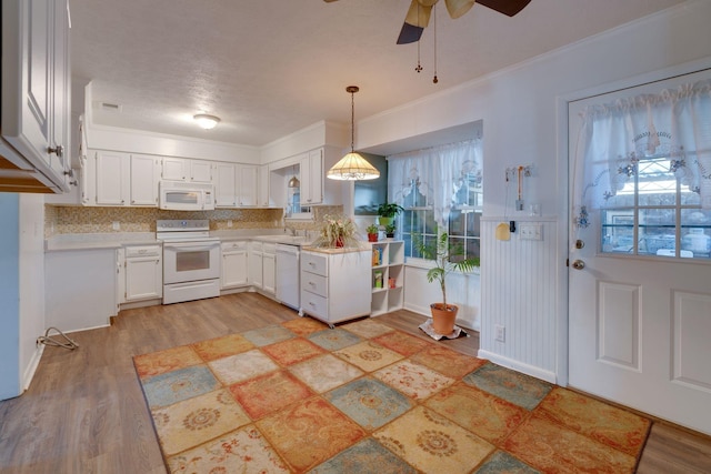 kitchen featuring a healthy amount of sunlight, white appliances, decorative light fixtures, and white cabinets