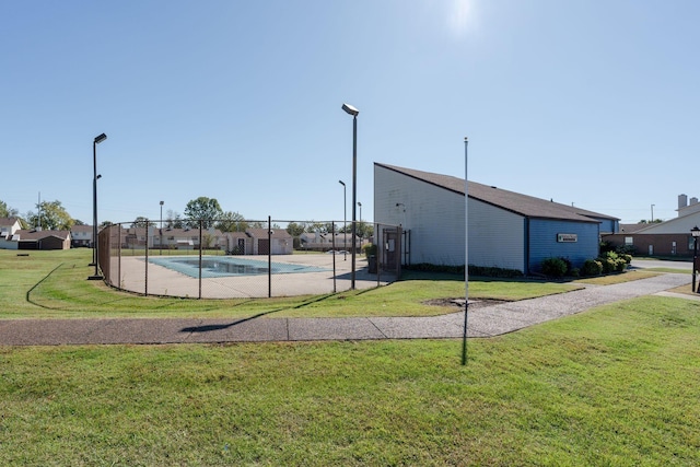 view of basketball court featuring a fenced in pool and a yard