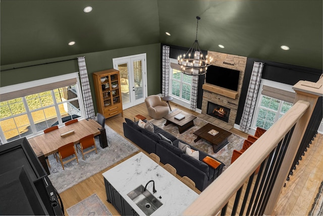 living room with hardwood / wood-style flooring, plenty of natural light, a fireplace, vaulted ceiling, and a chandelier