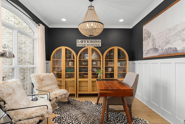 living area with ornamental molding, a notable chandelier, and light hardwood / wood-style floors