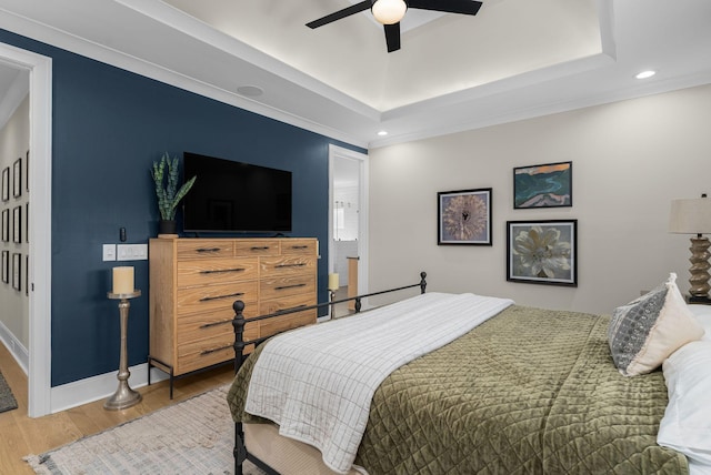 bedroom with crown molding, a tray ceiling, ceiling fan, and hardwood / wood-style flooring