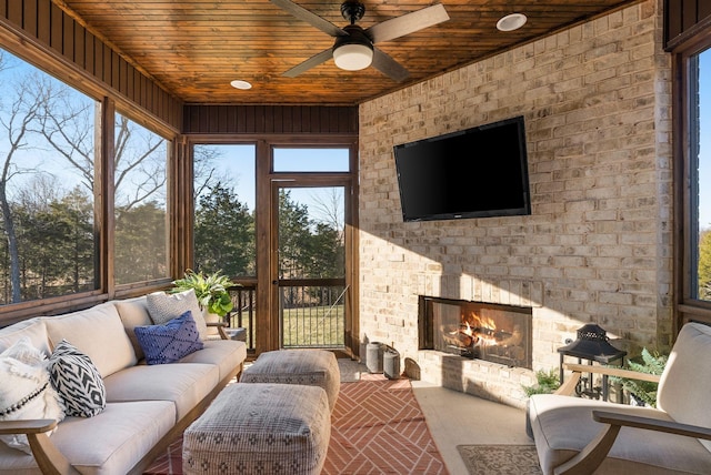 sunroom featuring an outdoor brick fireplace, ceiling fan, wooden ceiling, and a healthy amount of sunlight