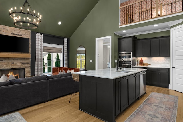 kitchen featuring sink, light hardwood / wood-style flooring, high vaulted ceiling, and an island with sink