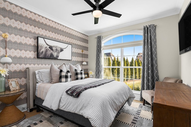 bedroom featuring crown molding, ceiling fan, wood-type flooring, and multiple windows