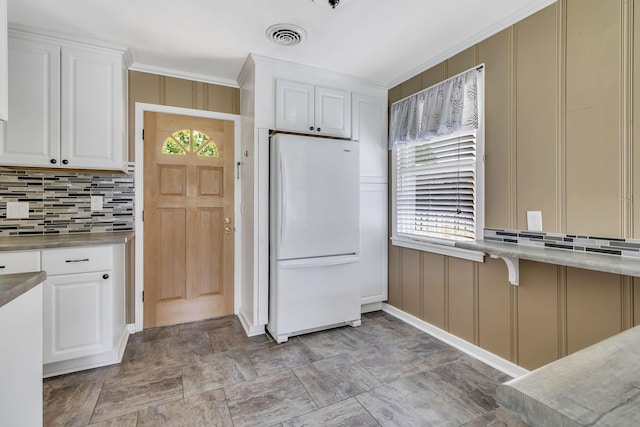 kitchen featuring white refrigerator, ornamental molding, a wealth of natural light, and white cabinets