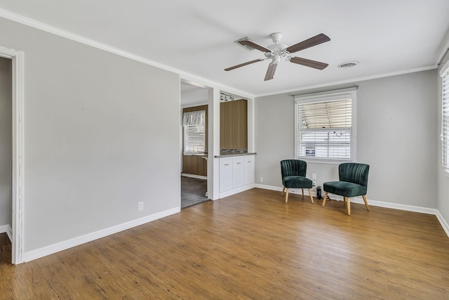 sitting room featuring ceiling fan, ornamental molding, and light wood-type flooring