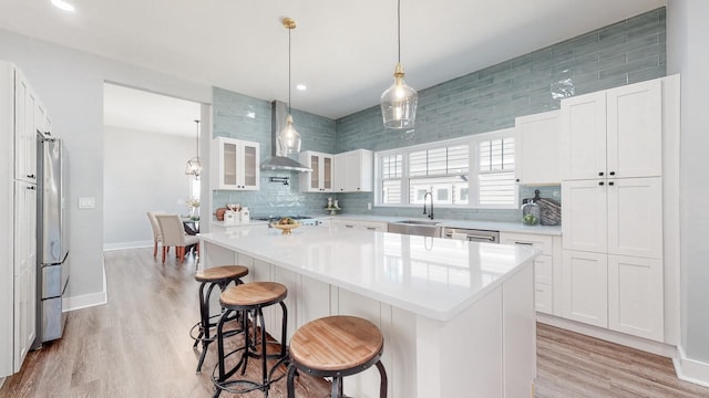 kitchen featuring sink, a breakfast bar area, a kitchen island, white cabinets, and backsplash