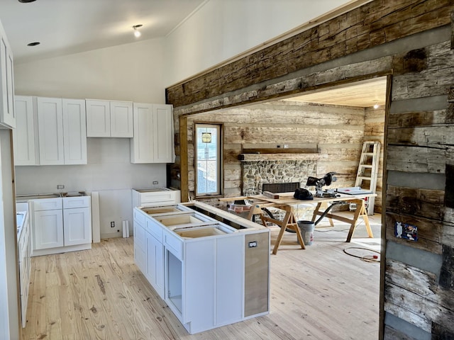 kitchen with white cabinetry, vaulted ceiling, and light hardwood / wood-style flooring