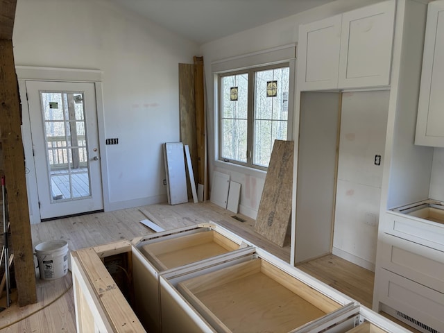 kitchen featuring white cabinetry, vaulted ceiling, and light hardwood / wood-style floors