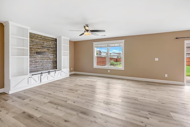 unfurnished living room featuring built in shelves, ceiling fan, and light wood-type flooring