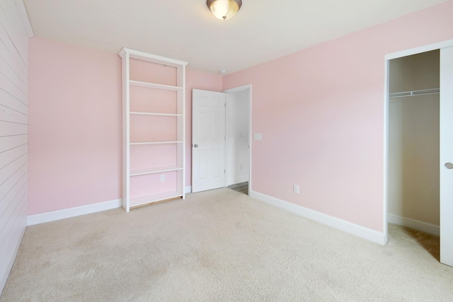 unfurnished bedroom with light colored carpet and a closet