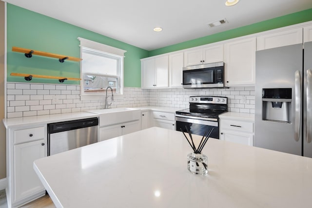 kitchen featuring stainless steel appliances, sink, white cabinets, and decorative backsplash