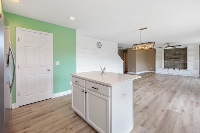 kitchen with pendant lighting, white cabinetry, stainless steel refrigerator with ice dispenser, a kitchen island, and light wood-type flooring