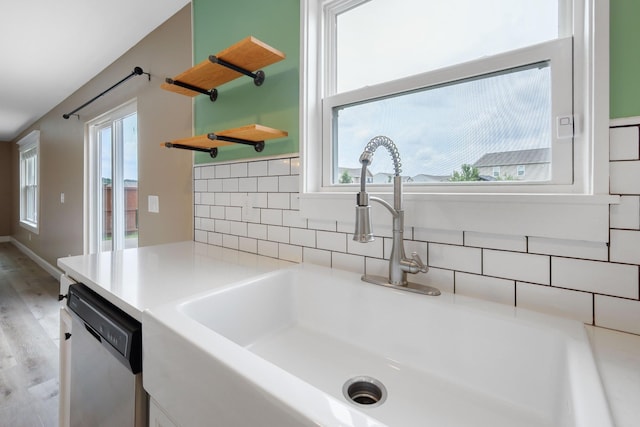 kitchen featuring plenty of natural light, dishwasher, sink, and light wood-type flooring