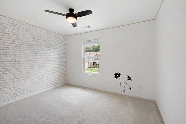 carpeted spare room featuring brick wall and ceiling fan