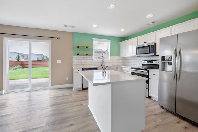 kitchen with white cabinetry, stainless steel appliances, a center island, and light hardwood / wood-style floors