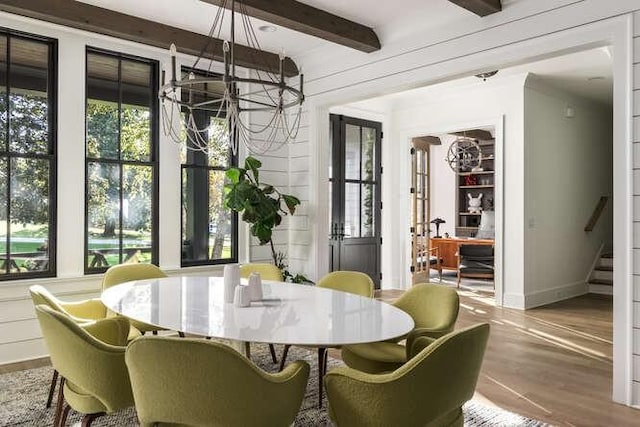 dining room with plenty of natural light, beam ceiling, a notable chandelier, and wood finished floors