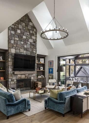 living room with high vaulted ceiling, a chandelier, wood finished floors, and a stone fireplace