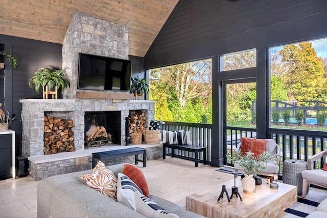 sunroom / solarium featuring wooden ceiling, vaulted ceiling, and a stone fireplace