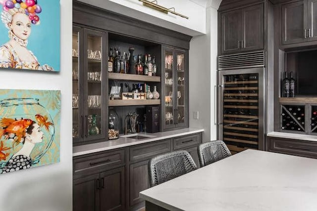 bar featuring sink, beverage cooler, and dark brown cabinetry