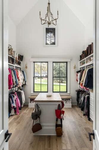 walk in closet featuring high vaulted ceiling, light wood finished floors, and an inviting chandelier