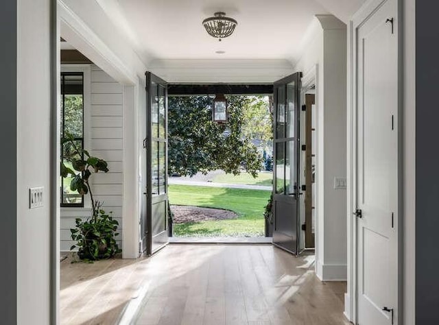 entryway featuring ornamental molding and light wood-type flooring