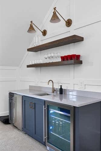 bar with wine cooler, blue cabinets, vaulted ceiling, and sink