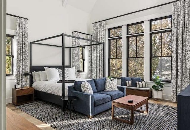 bedroom with high vaulted ceiling, multiple windows, and wood finished floors