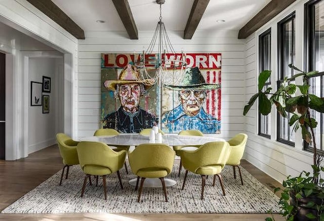 dining room with wooden walls, baseboards, beam ceiling, and wood finished floors