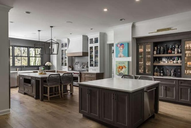 kitchen featuring dark wood-type flooring, a breakfast bar area, a kitchen island, custom range hood, and stainless steel appliances