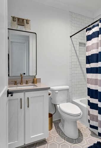 bathroom with toilet, vanity, and shower / tub combo with curtain