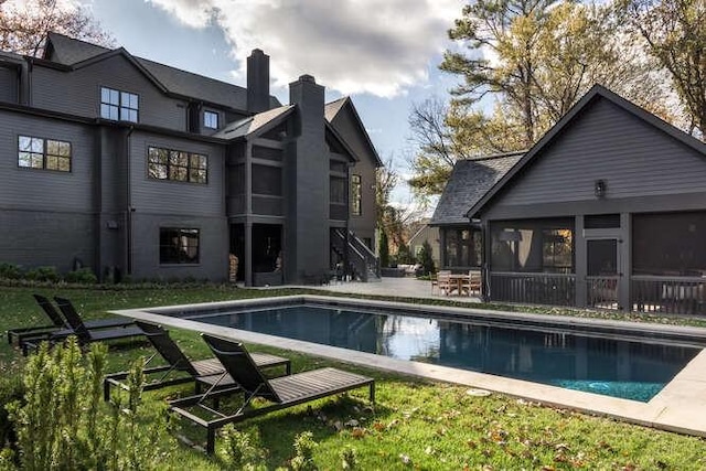 outdoor pool featuring a patio, a lawn, and a sunroom