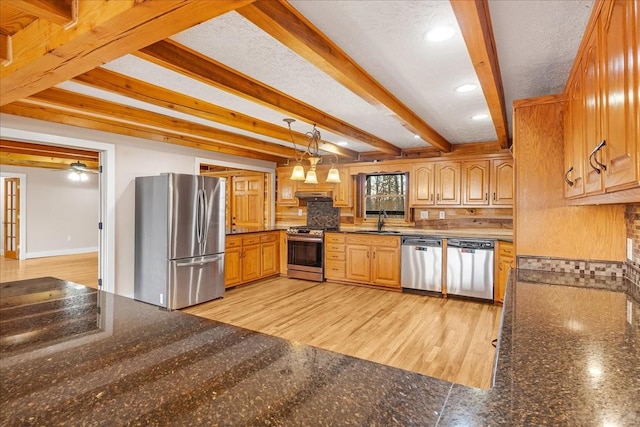 kitchen with sink, decorative light fixtures, appliances with stainless steel finishes, beamed ceiling, and backsplash