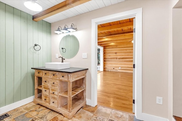 bathroom with vanity, beam ceiling, and wooden walls