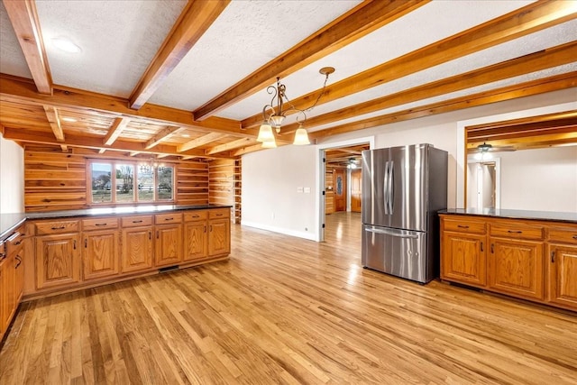 kitchen with light hardwood / wood-style floors, wood walls, stainless steel refrigerator, and decorative light fixtures