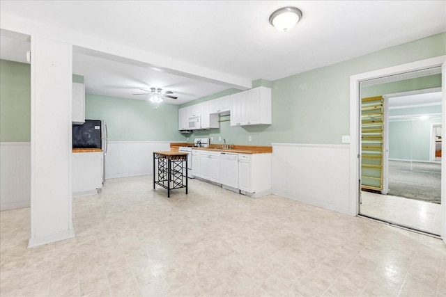 kitchen with white cabinetry, butcher block counters, a kitchen bar, ceiling fan, and white appliances