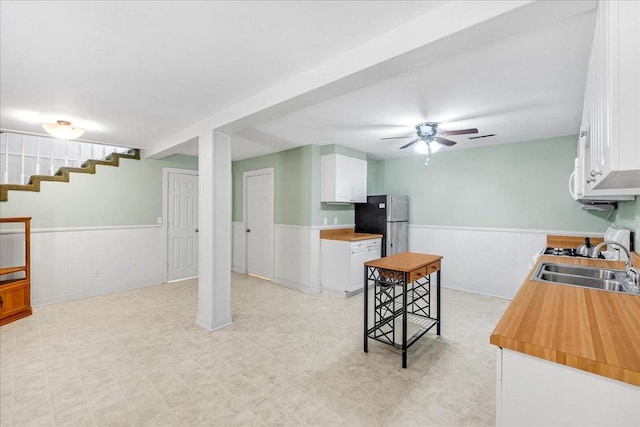 kitchen featuring stainless steel refrigerator, ceiling fan, sink, and white cabinets