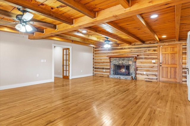 unfurnished living room with wood ceiling, ceiling fan, rustic walls, a fireplace, and light hardwood / wood-style floors