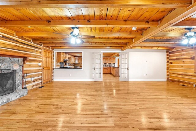 unfurnished living room featuring french doors, a fireplace, log walls, and light hardwood / wood-style floors