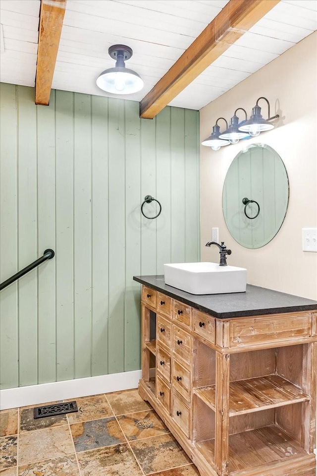 bathroom with beamed ceiling, vanity, and wooden walls