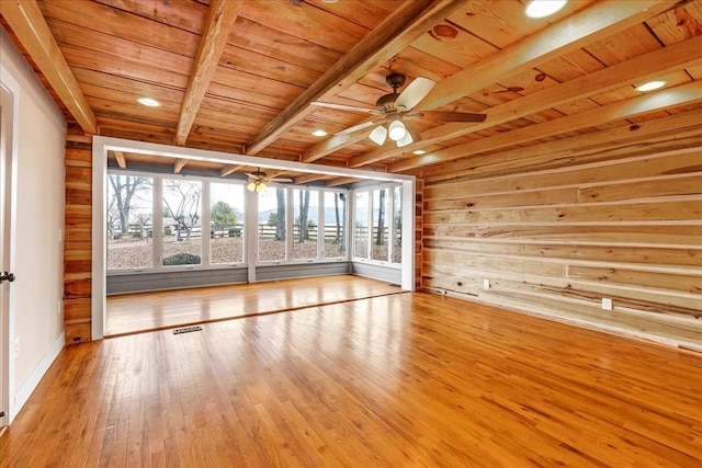 interior space featuring wood walls, light hardwood / wood-style flooring, wooden ceiling, beamed ceiling, and ceiling fan