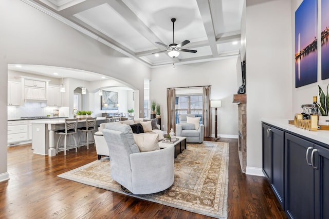 living room with ceiling fan, beam ceiling, dark hardwood / wood-style floors, coffered ceiling, and a fireplace