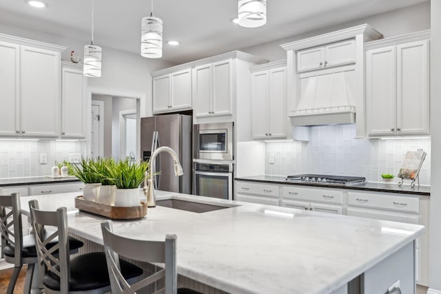 kitchen with pendant lighting, a large island, white cabinetry, and stainless steel appliances